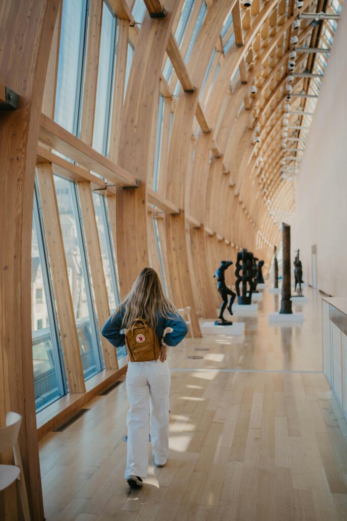 Woman with a backpack exploring the modern art gallery with wooden architecture.