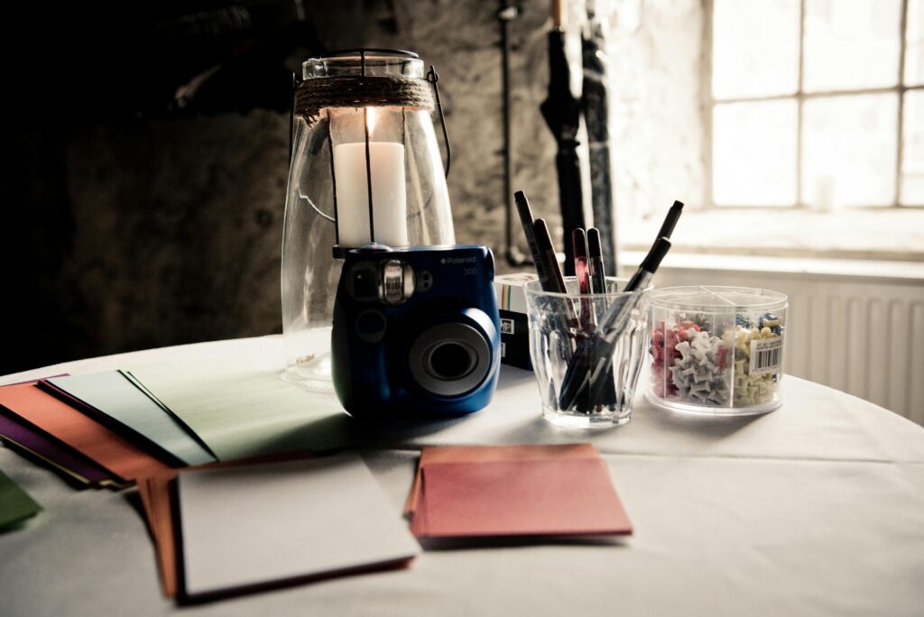 A workspace featuring an instant camera, candles, and office supplies, creating a modern aesthetic.