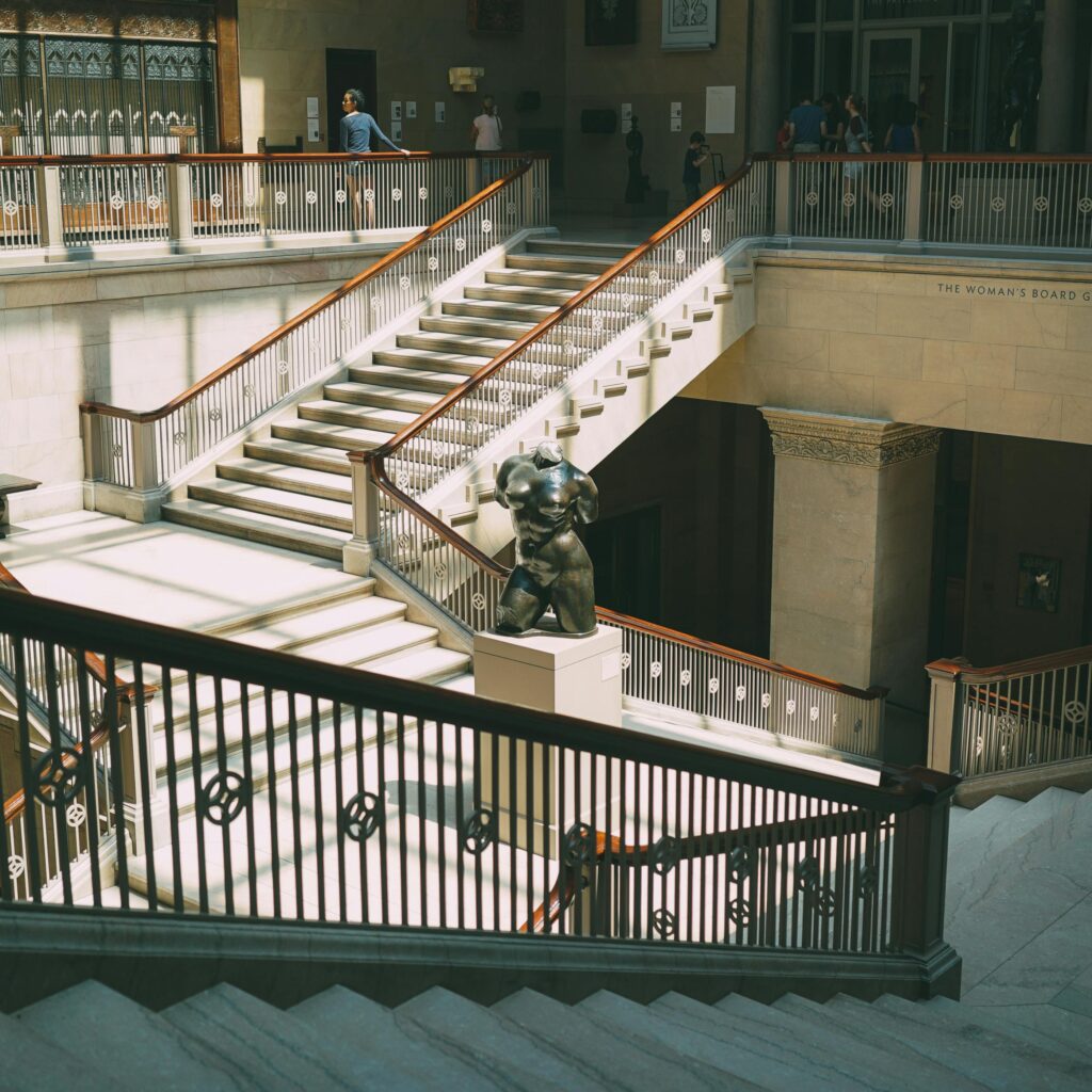 Elegant staircase in a Chicago museum with artistic sculptures and soft lighting.