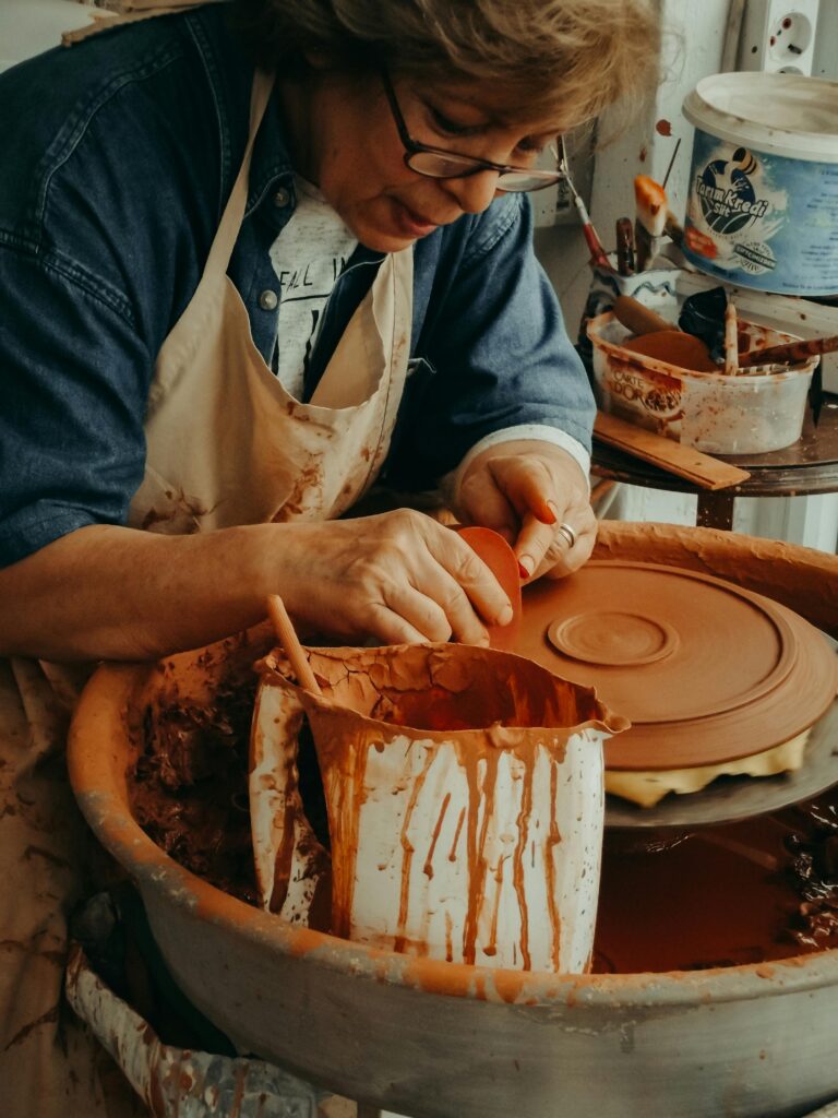 A woman intensely crafting pottery on a wheel, showcasing skilled craftsmanship.