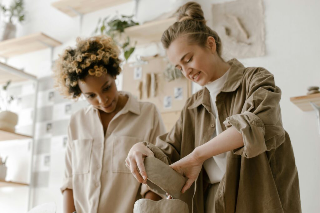 Two women engaged in crafting pottery in an artistic and relaxed workshop setting.