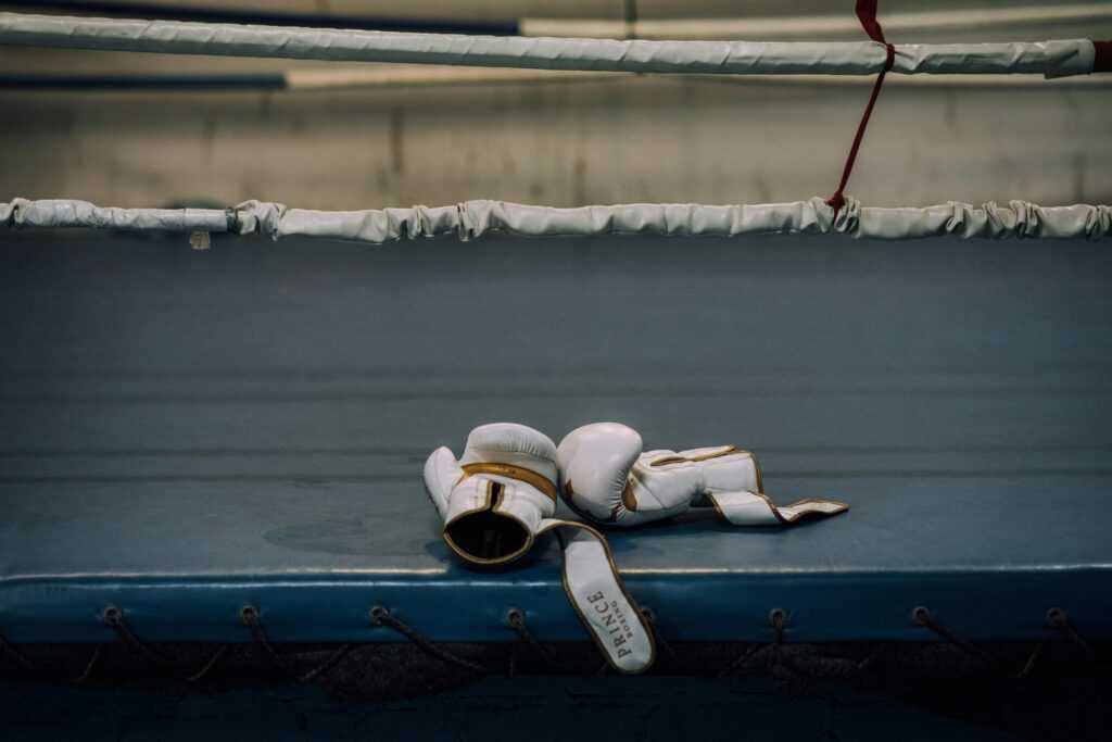 White boxing gloves resting inside an empty boxing ring, symbolizing sports intensity.